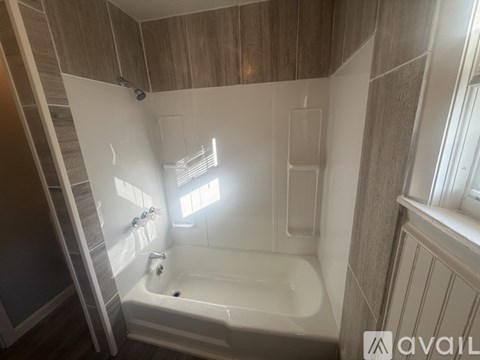 A bathroom with a bathtub and a window.