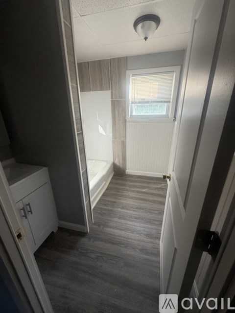 A hallway with a white door and a window with blinds.