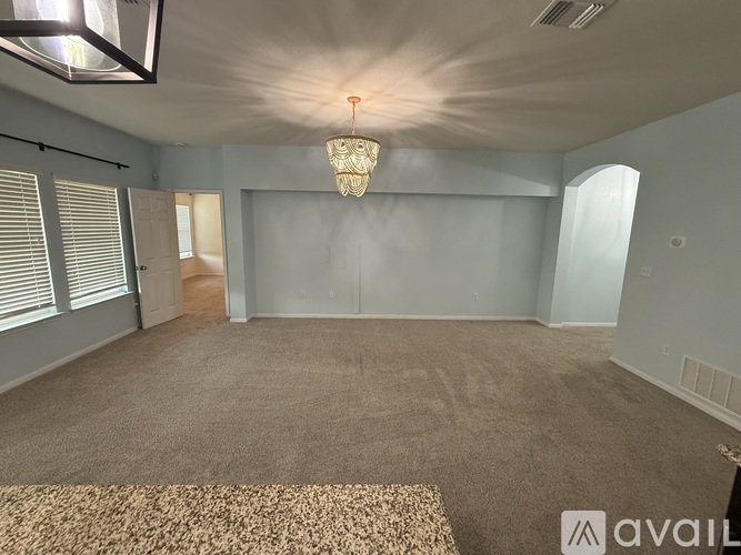 A spacious room with a carpeted floor and a chandelier hanging from the ceiling.