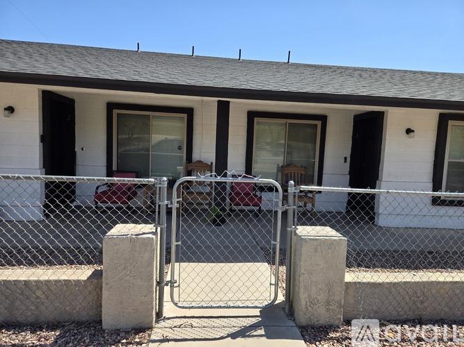 A white house with a grey roof and a chain link fence.