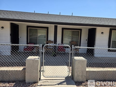 A white house with a grey roof and a chain link fence.