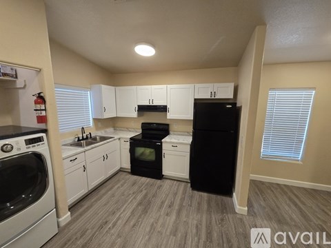 A kitchen with a black refrigerator, white cabinets, and a stove top oven.