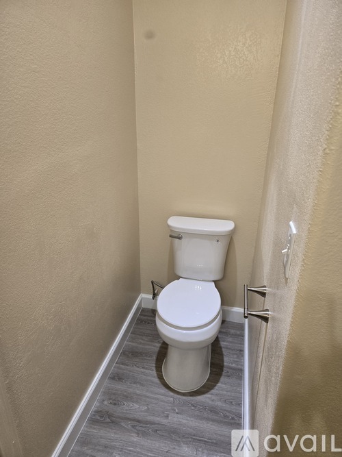 A white toilet in a small bathroom with beige walls.