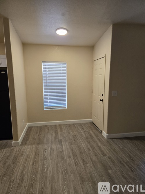 A room with a wooden floor and a window with blinds.