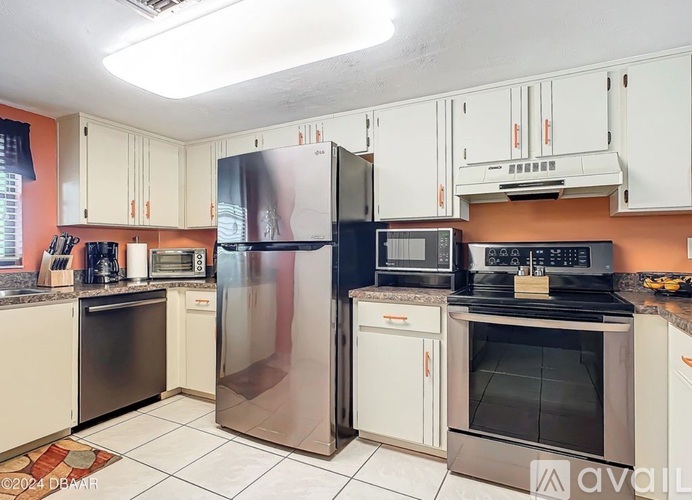A kitchen with white cabinets and a black refrigerator.