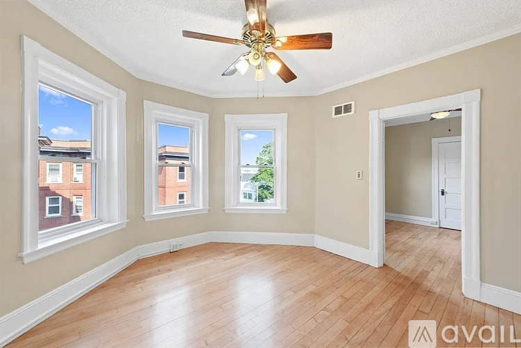 A room with a ceiling fan and three windows.