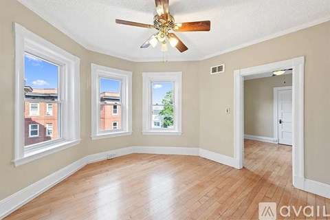 A room with a ceiling fan and three windows.