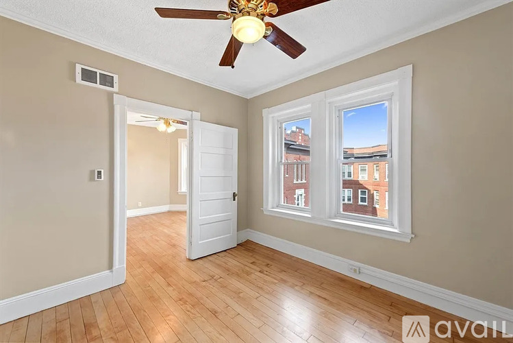 A room with a ceiling fan and a window overlooking a city.