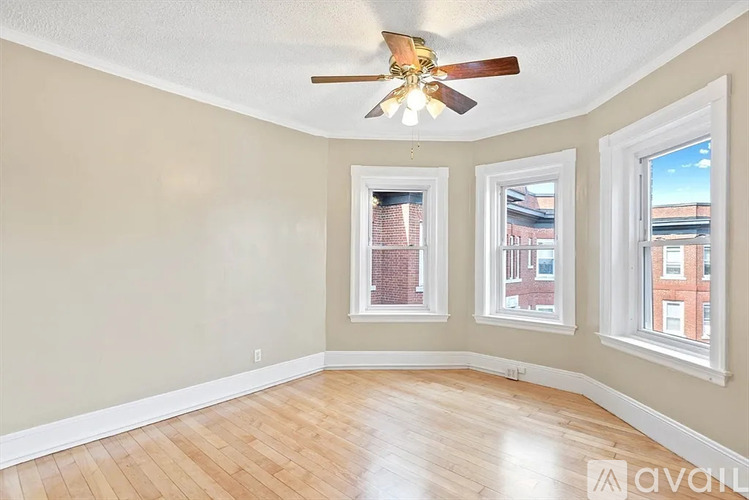 A room with a ceiling fan and three windows.