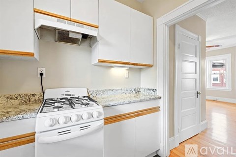 A white stove is in a kitchen with wooden cabinets.