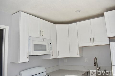 A kitchen with white cabinets and a white microwave.