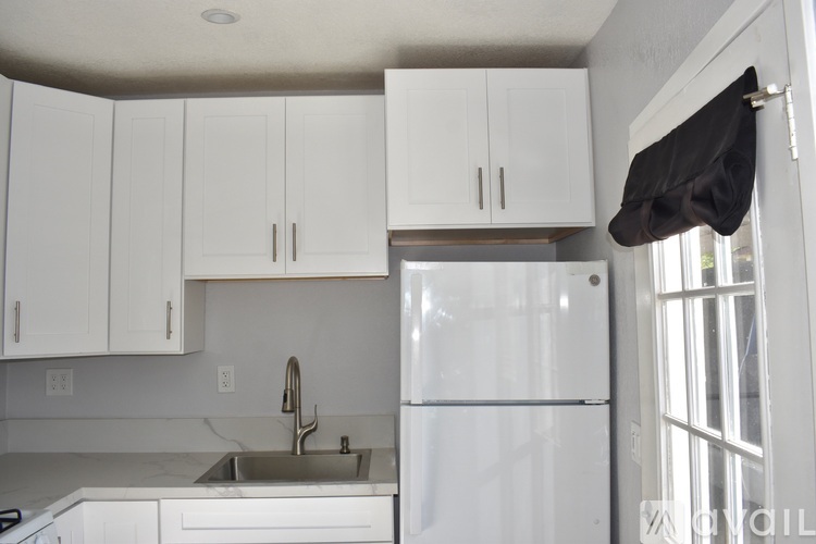 A kitchen with white cabinets and a white refrigerator.