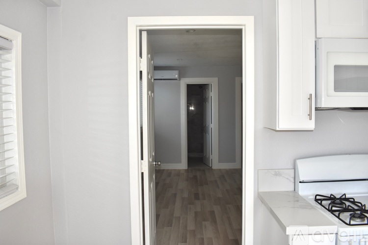A white kitchen with a stove and a doorway leading to another room.