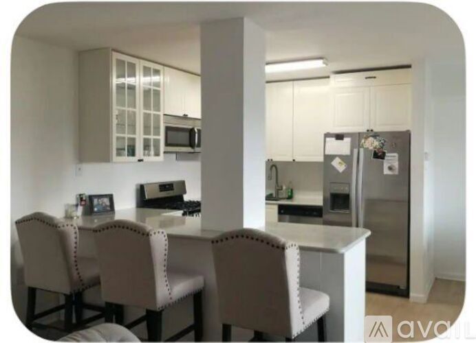A kitchen with a table and chairs in the foreground and a refrigerator in the background.