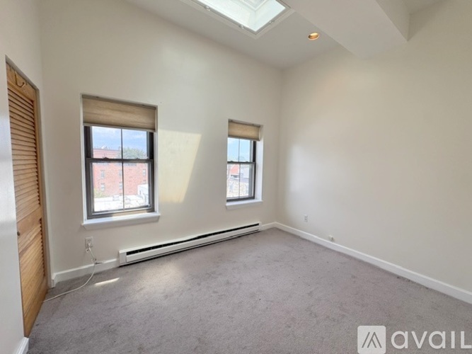 A spacious room with two windows and a skylight.