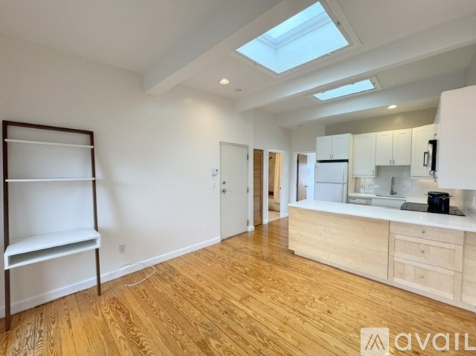 A spacious kitchen with wooden floors and a skylight.