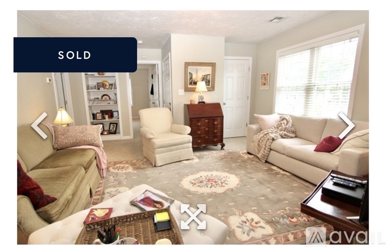 A living room with a sofa, armchair, and coffee table is for sale.