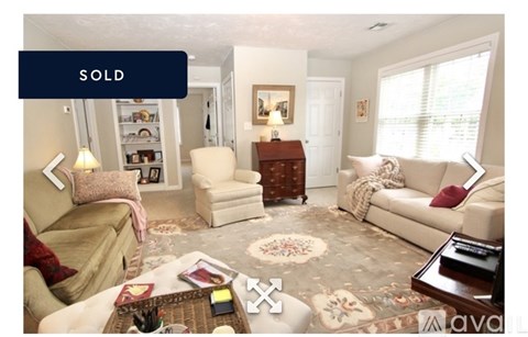 A living room with a sofa, armchair, and coffee table is for sale.