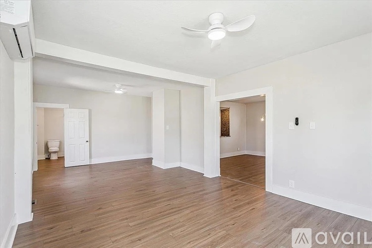 A spacious room with wooden flooring and a ceiling fan.