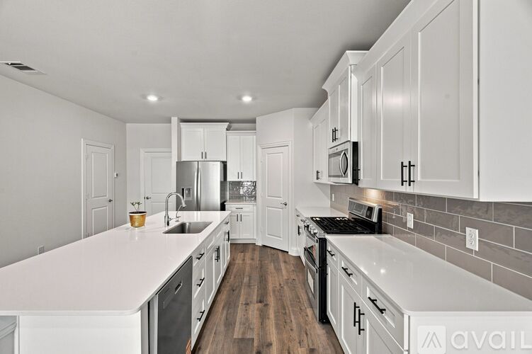 A modern kitchen with white cabinets and a wooden floor.