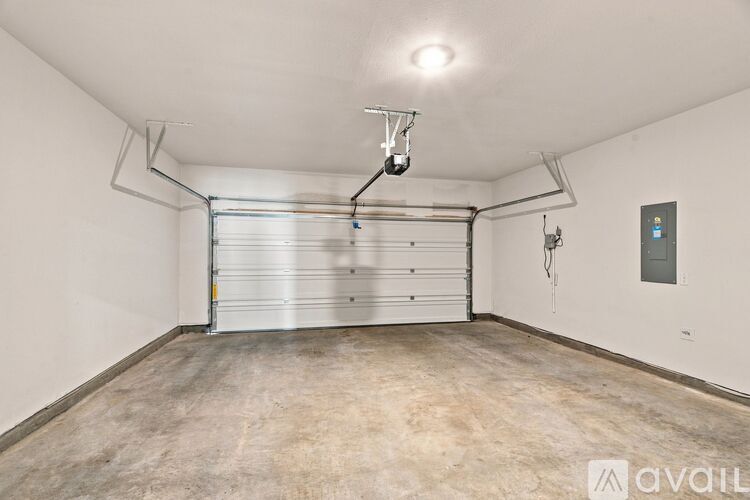 A spacious garage with a closed white door and a hanging light fixture.