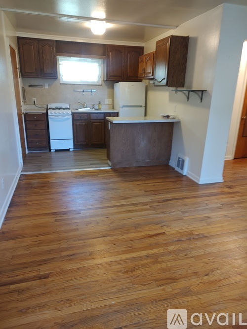 A kitchen with wooden floors and white appliances.