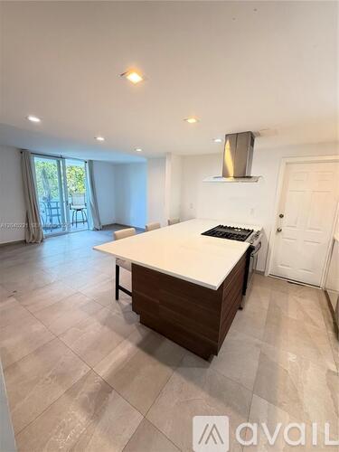 A kitchen with a large island and a stove hood.