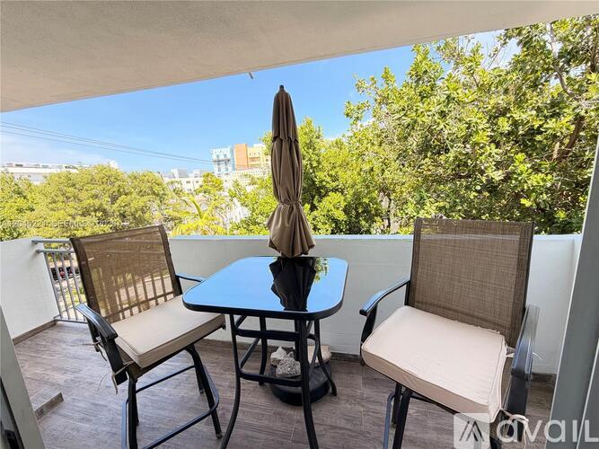 A patio with a table, two chairs, and an umbrella.