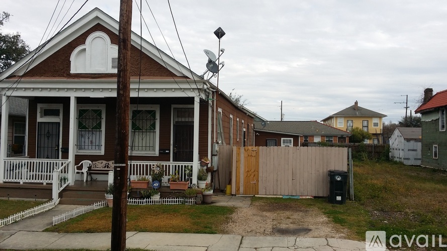 A house with a porch and a fence in front of it.