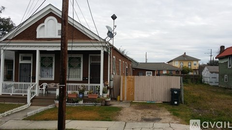 A house with a porch and a fence in front of it.