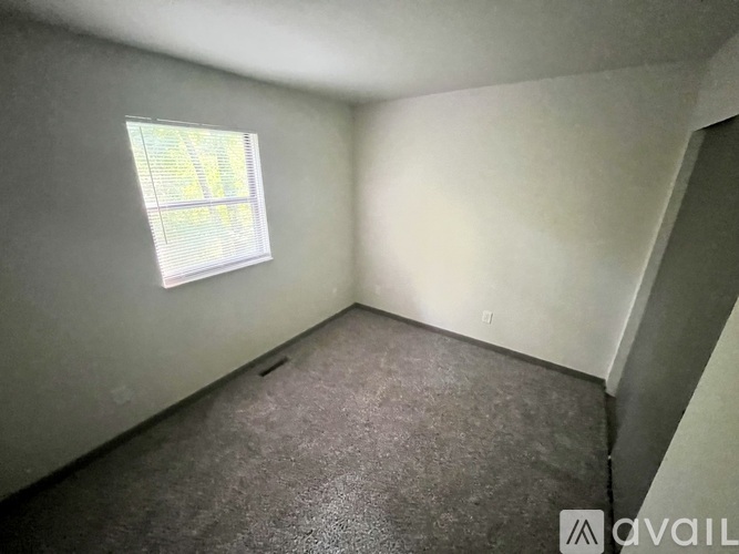 A room with a window and carpeted floor.