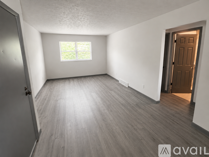 A room with a wooden floor and a window letting in light.