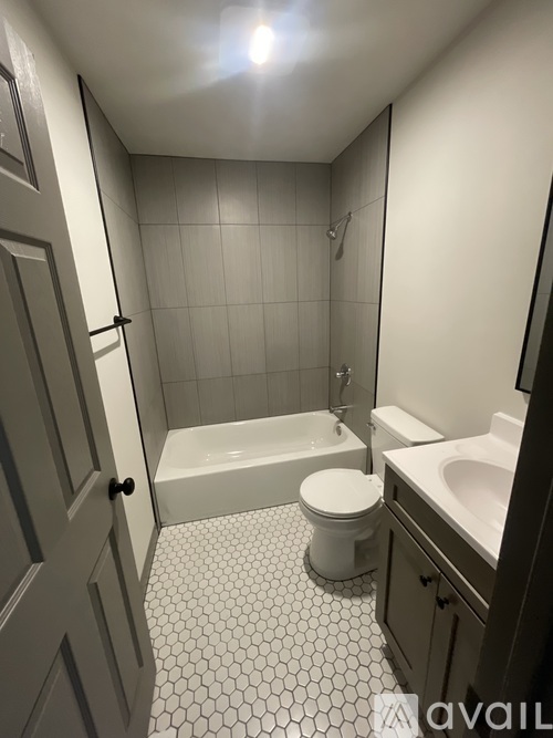 A white toilet sits in a bathroom with a white tiled floor and walls.