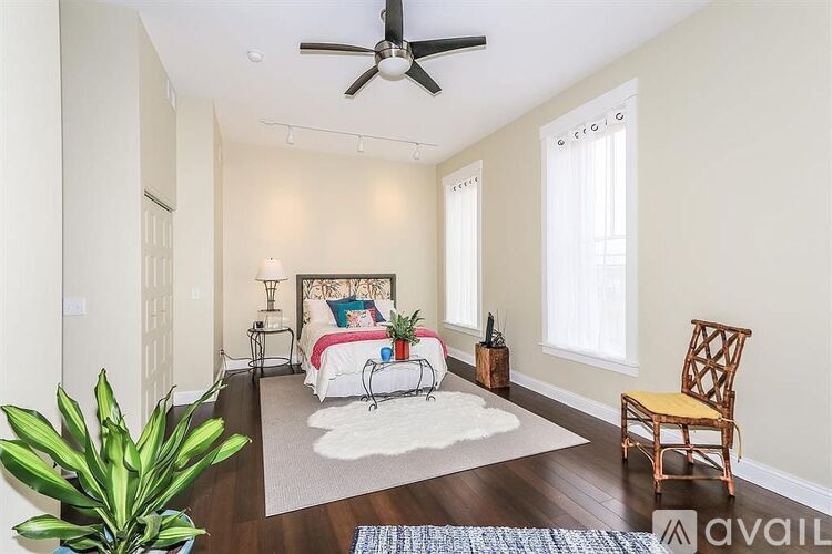 A bedroom with a bed, chair, and plant.