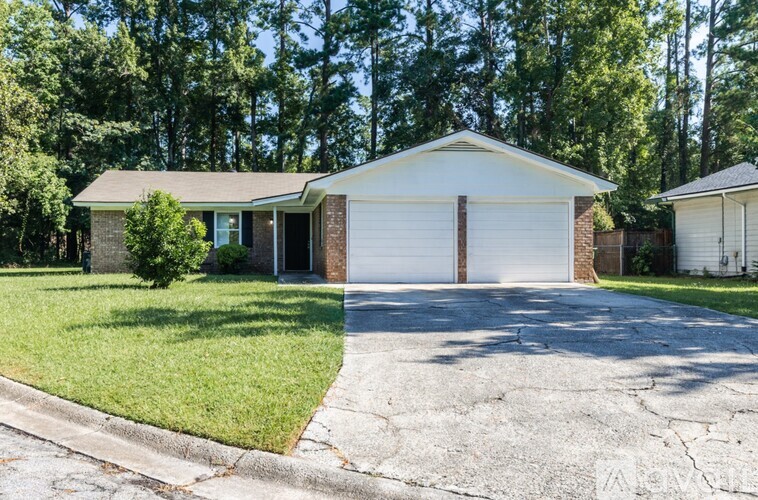 A house with a white garage door is surrounded by trees.