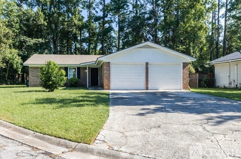 A house with a white garage door is surrounded by trees.