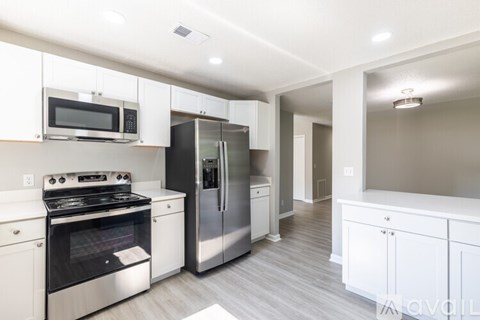 A modern kitchen with white cabinets and stainless steel appliances.