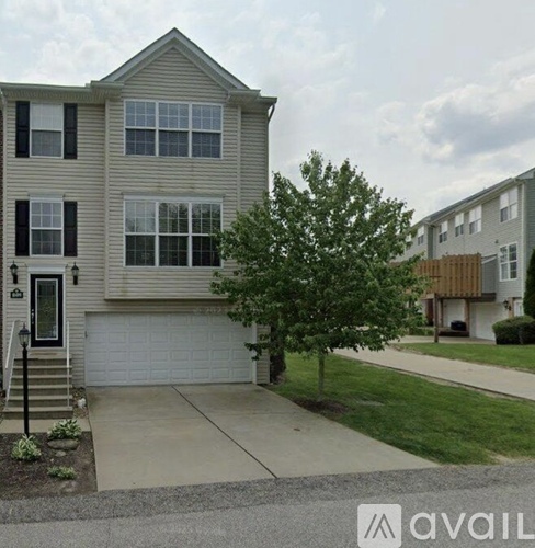 A two-story house with a garage and a tree in front.