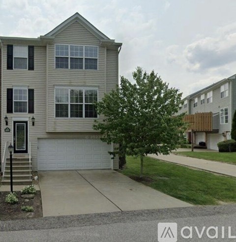 A two-story house with a garage and a tree in front.