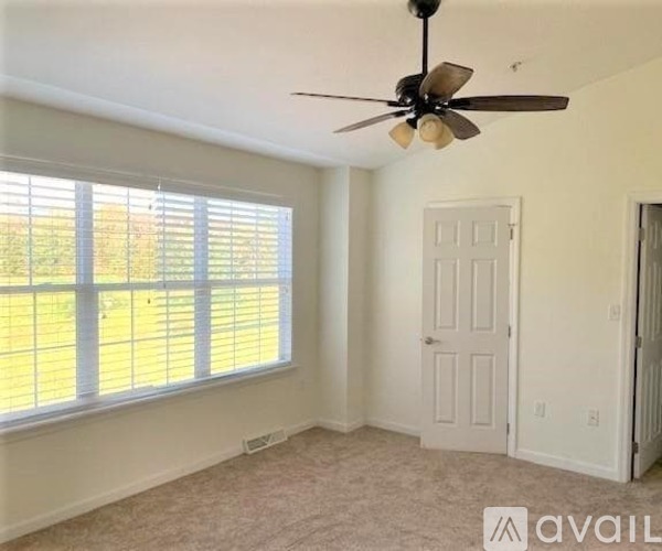 A room with a ceiling fan and a window with blinds.