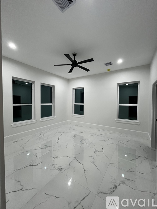 A spacious room with marble flooring and a ceiling fan.