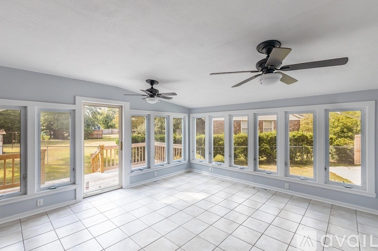 A sunny day in a spacious room with a ceiling fan and sliding glass doors.