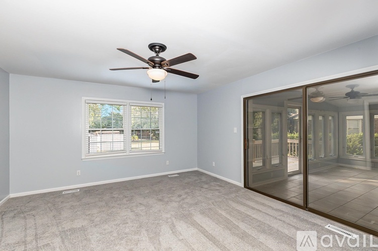 A room with a ceiling fan and a window with blinds.