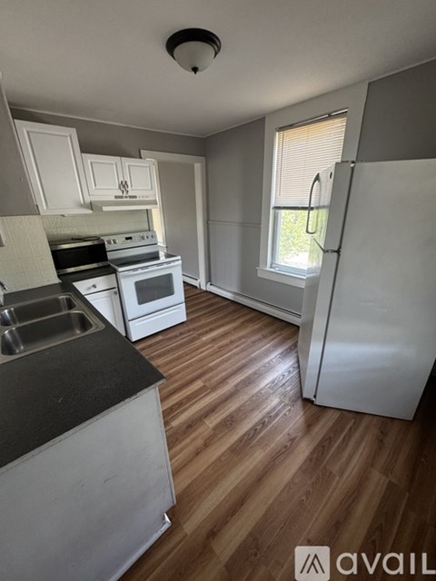 A kitchen with white appliances and wooden floors.