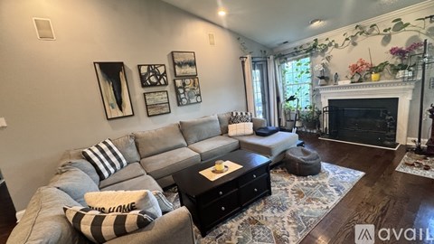 A living room with a grey couch and a fireplace.