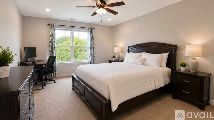 A bedroom with a large bed, a desk with a chair, and a ceiling fan.