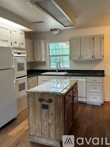 A kitchen with a wooden island in the middle.