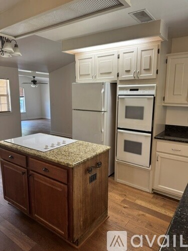 A kitchen with a granite countertop and wooden cabinets.