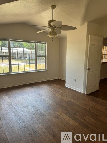 A room with a fan and wooden flooring.