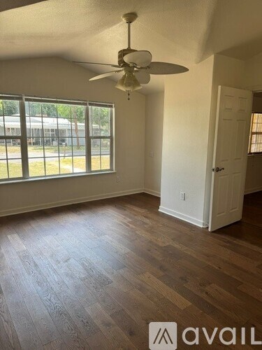 A room with a fan and wooden flooring.